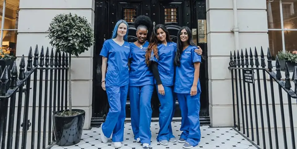 Four nurses in blue scrubs outside a Georgian clinic entrance for Ultherapy skin lifting in Amsterdam